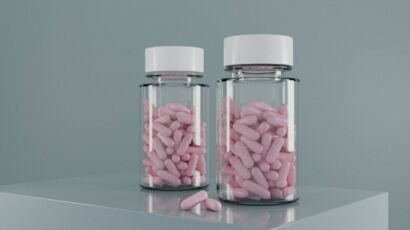 Two pill bottles filled with pink medication.